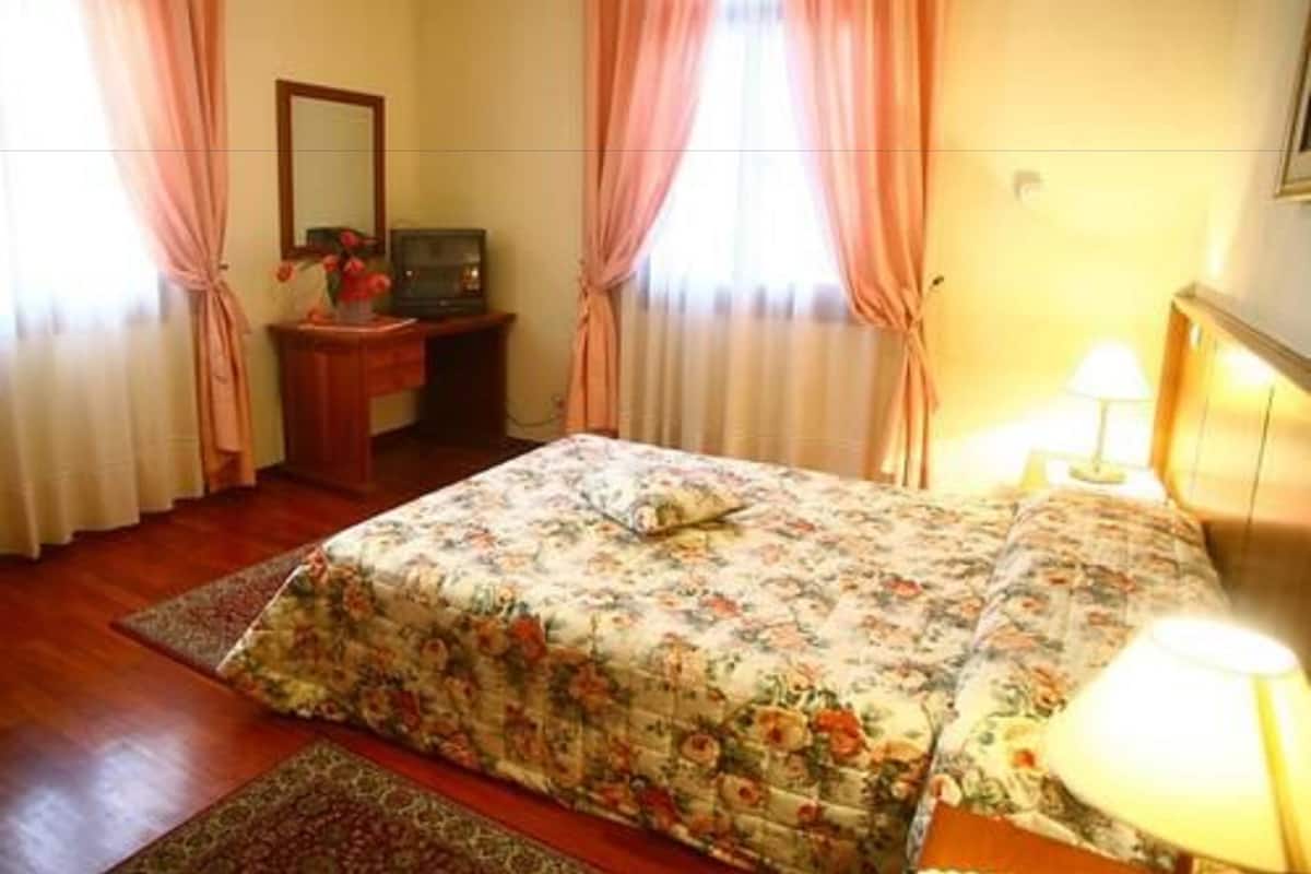 Un dormitorio con cama, escritorio, lámpara y cortinas.