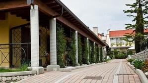 Een verhard pad dat leidt naar een gebouw met kolommen en een overdekte ingang.