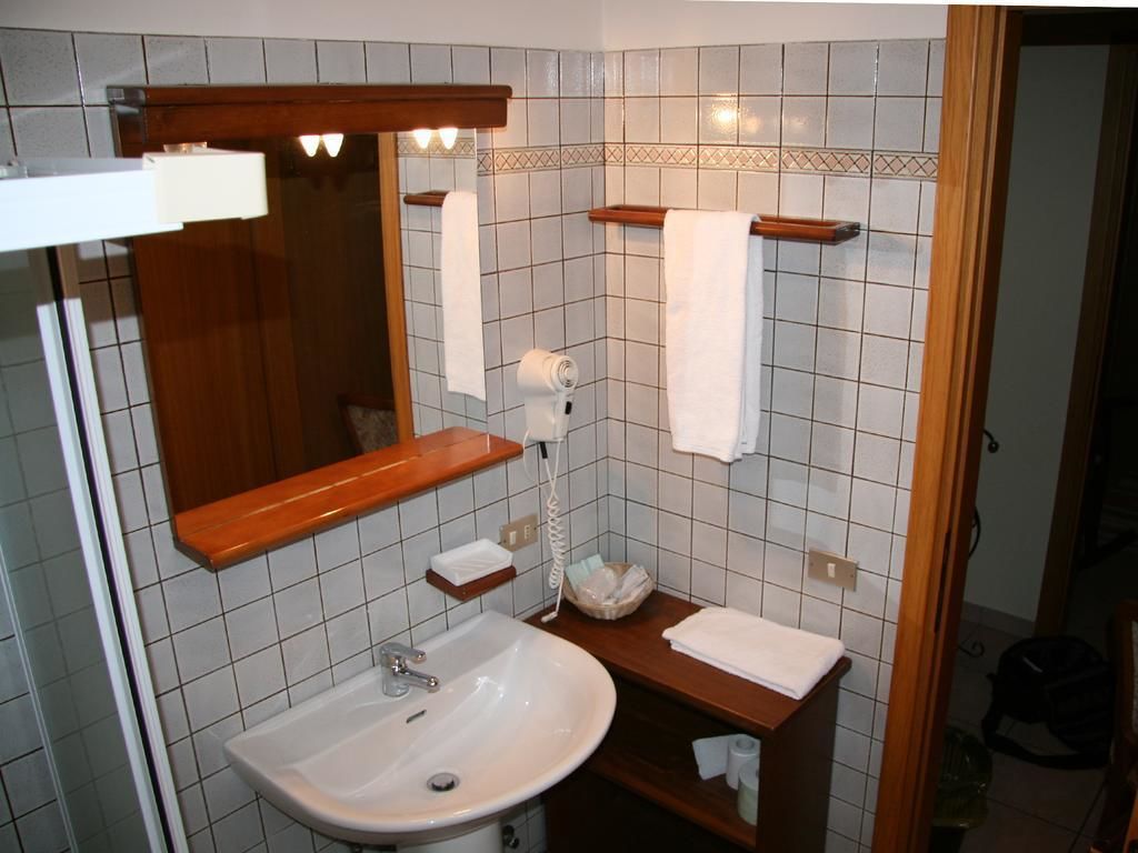 A bathroom with a white sink, wooden vanity, and a mirror.