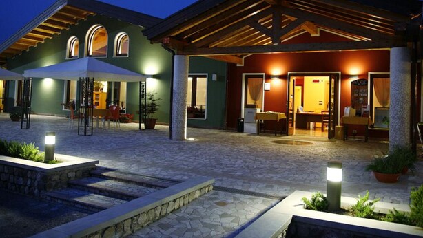 Een hotel met een overdekt terras, stenen vloeren en een goed verlichte entree.