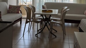 A hotel room with a balcony, a dining table with chairs, a sofa, and a view of the sea. - Hakan Apart Hotel (Erdemli)