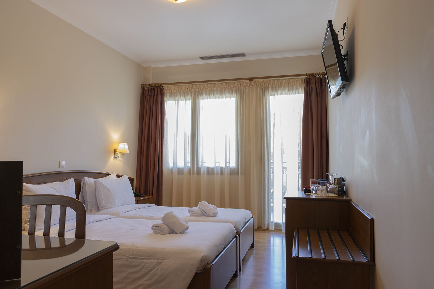 Een hotelkamer met twee bedden, een bureau, een stoel, een televisie en een klein tafeltje met toiletartikelen.