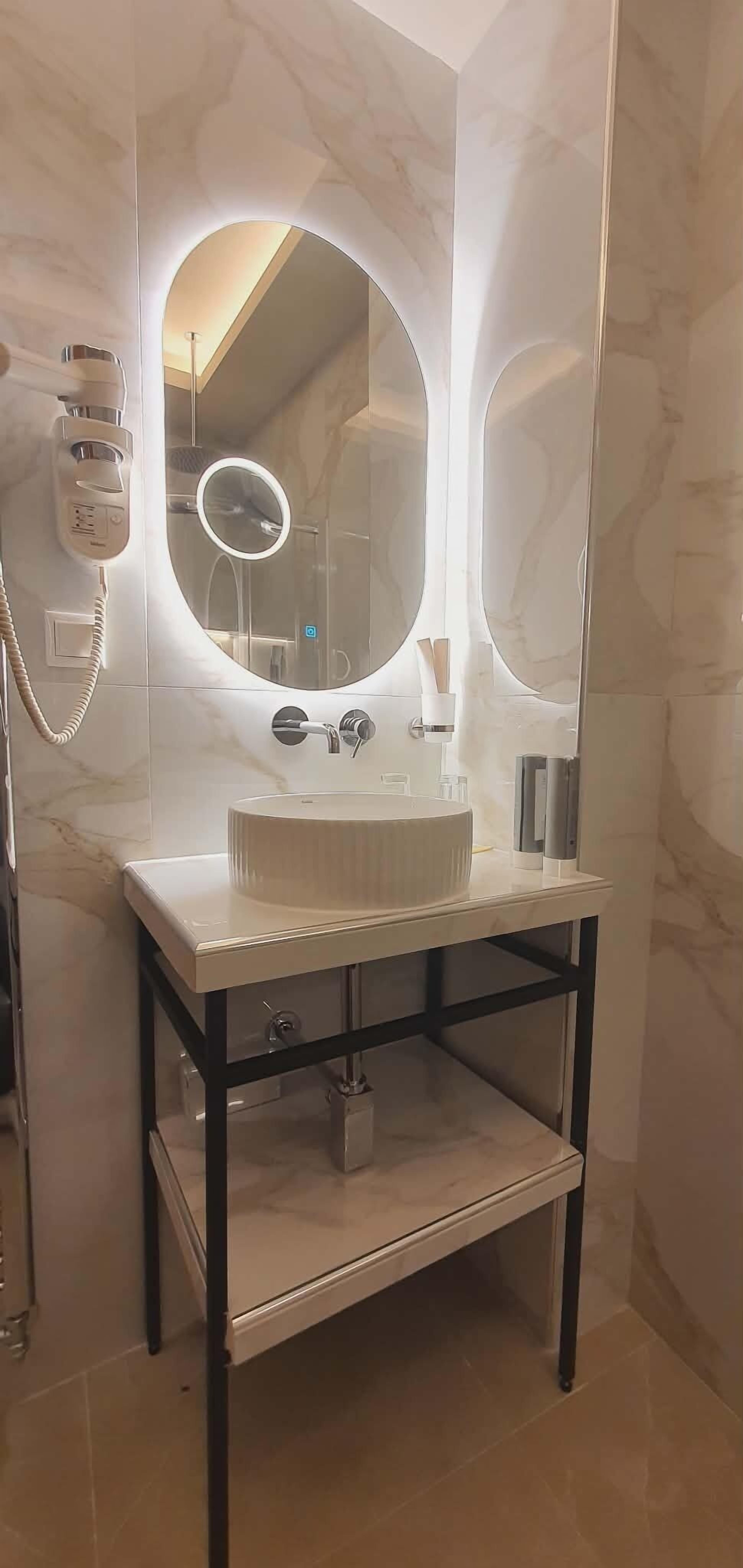 A bathroom with a marble vanity, a large mirror, and a hairdryer.