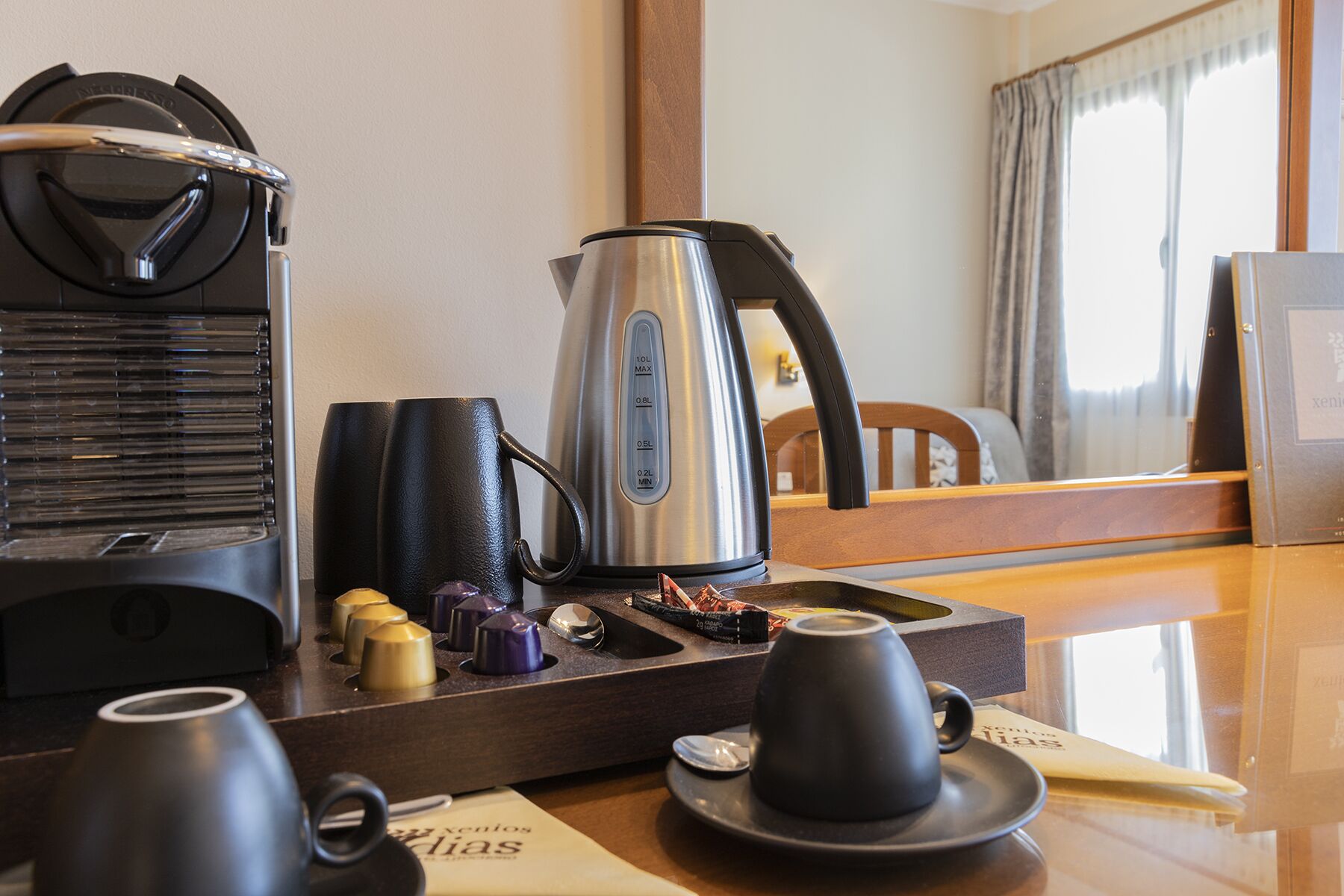 Habitación de hotel con estación de café, que incluye cafetera, tazas y terrones de azúcar.