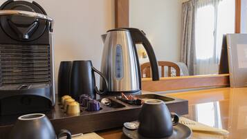A hotel room with a coffee station, including a coffee maker, cups, and sugar cubes.