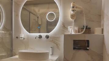 A modern bathroom with a round mirror, a sink, a toilet, and a hairdryer.