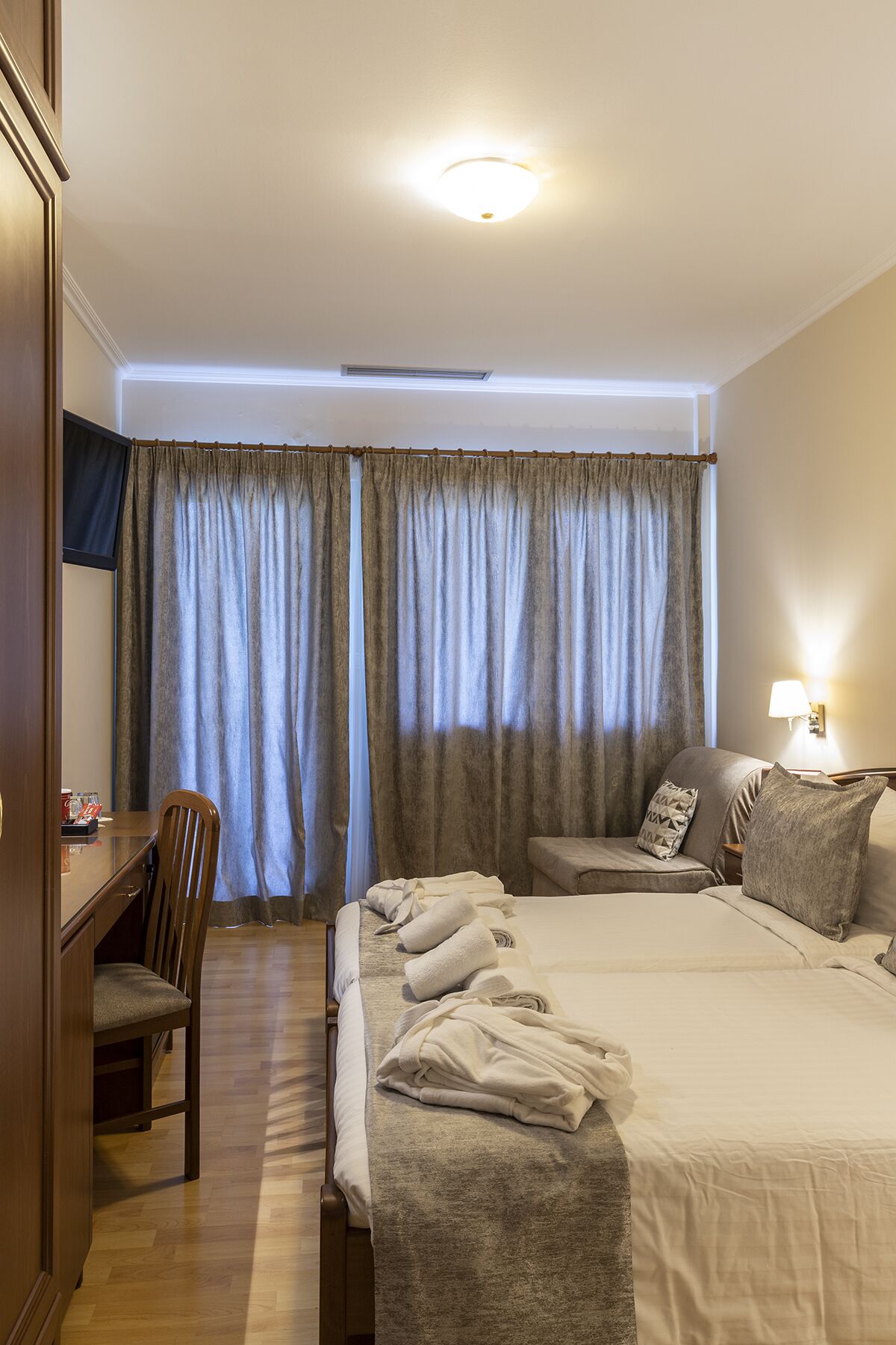 A hotel room with a bed, a desk, a chair, and a TV.