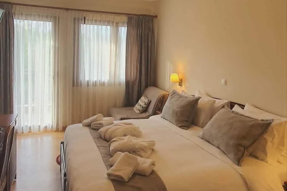 Una habitación de hotel con una cama grande, un escritorio y una ventana con cortinas.