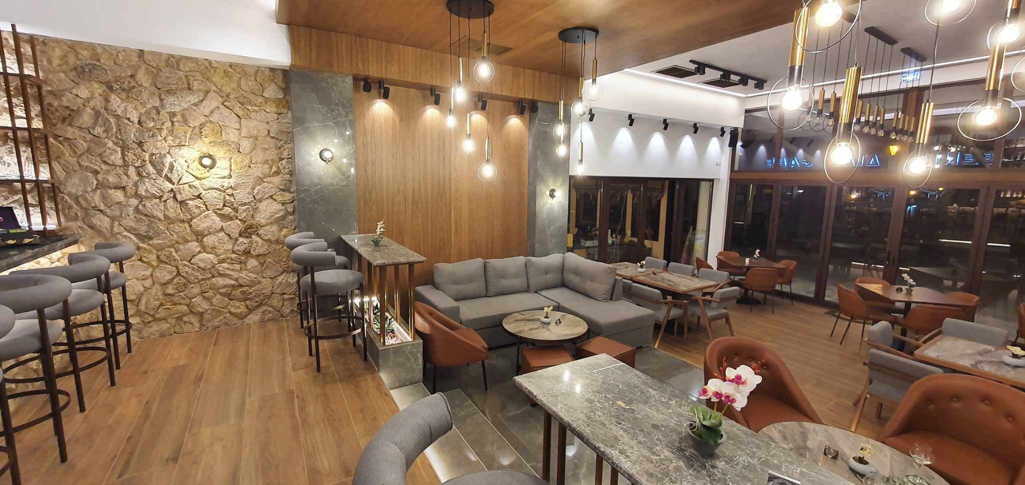 Ein modernes Restaurantambiente mit einer Wand aus Stein, Holzverkleidung und einer Kombination aus Bar- und Essbereich.