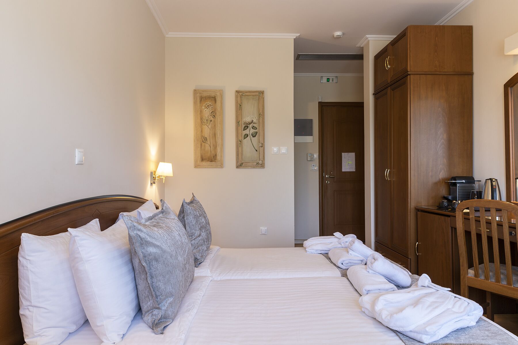 Habitación de hotel con cama, almohadas, armario y una mesita con tetera.