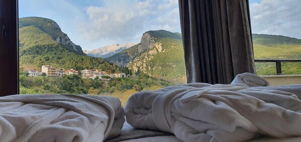 A hotel room with a bed and a view of a mountainous landscape.