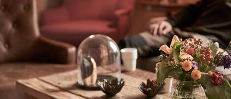 A wooden table with a glass vase containing flowers, a metal dome, and a small bowl.