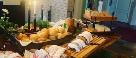 Una mesa de buffet con panes y pasteles diversos, velas y un ambiente rústico con manteles de madera.