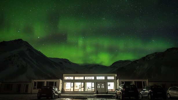 Un edificio con un letrero que dice "Viking Guesthouse" bajo un cielo nocturno con la aurora boreal.