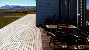 Terraza de madera con mobiliario exterior y vistas a las montañas.
