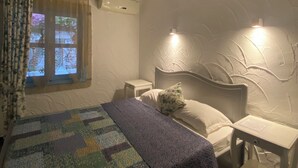 A bedroom with a bed, bedside tables, a window with curtains, a wall-mounted light, and a ceiling fan. - Cakirbey Otel (Cesme)