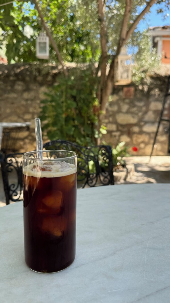 A glass of iced tea on a table with a metal chair in the background. - Cakirbey Otel (Cesme)