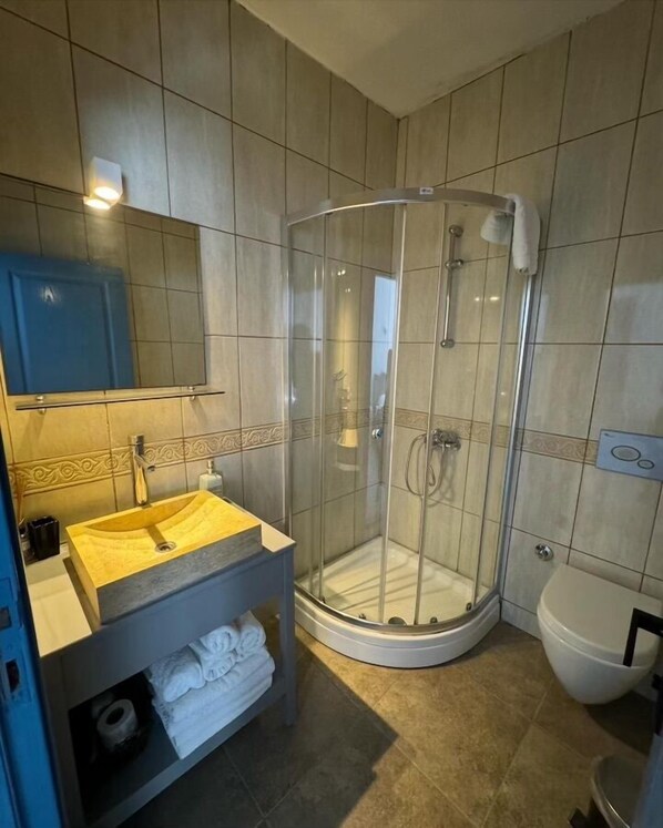 A modern bathroom with a glass-enclosed shower, a sink with a yellow countertop, and a toilet.
