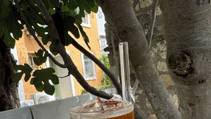 A glass of iced tea with a straw on a marble surface, with a tree and a building in the background. - Cakirbey Otel (Cesme)