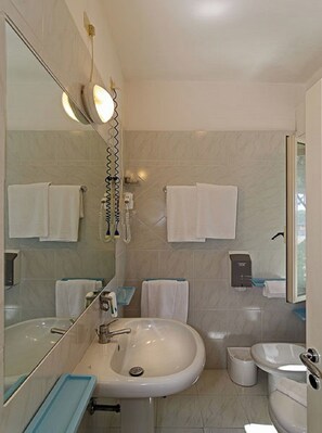 A bathroom with a sink, mirror, towel rack, and a shower.