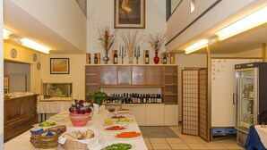 Un comedor con una larga mesa dispuesta para una comida, rodeado de estanterías con botellas y objetos decorativos.