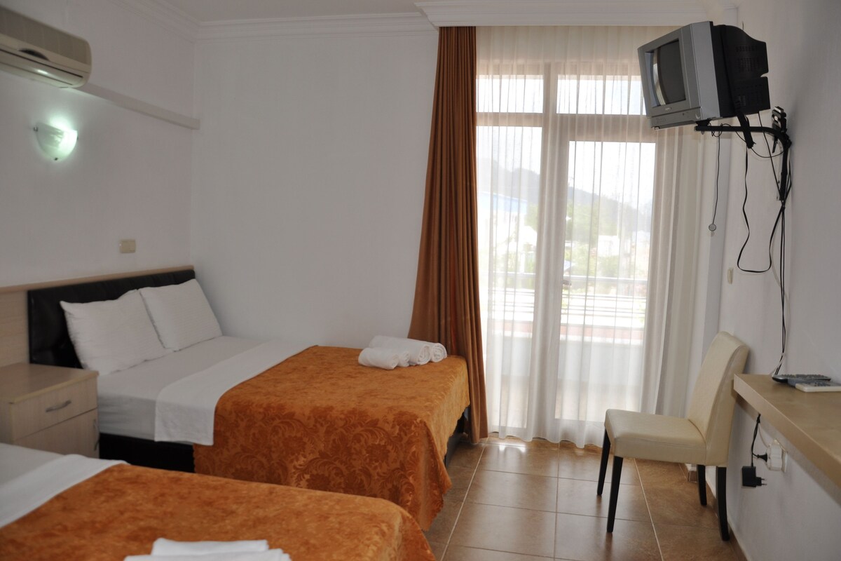 A hotel room with two beds, a desk, a chair, and a TV mounted on the wall.