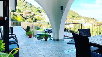 A covered outdoor seating area with a view of a hilly landscape.