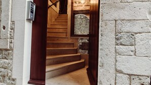 Un arco de piedra que da a una escalera con un interior moderno, que incluye un candelabro y un teclado de seguridad.