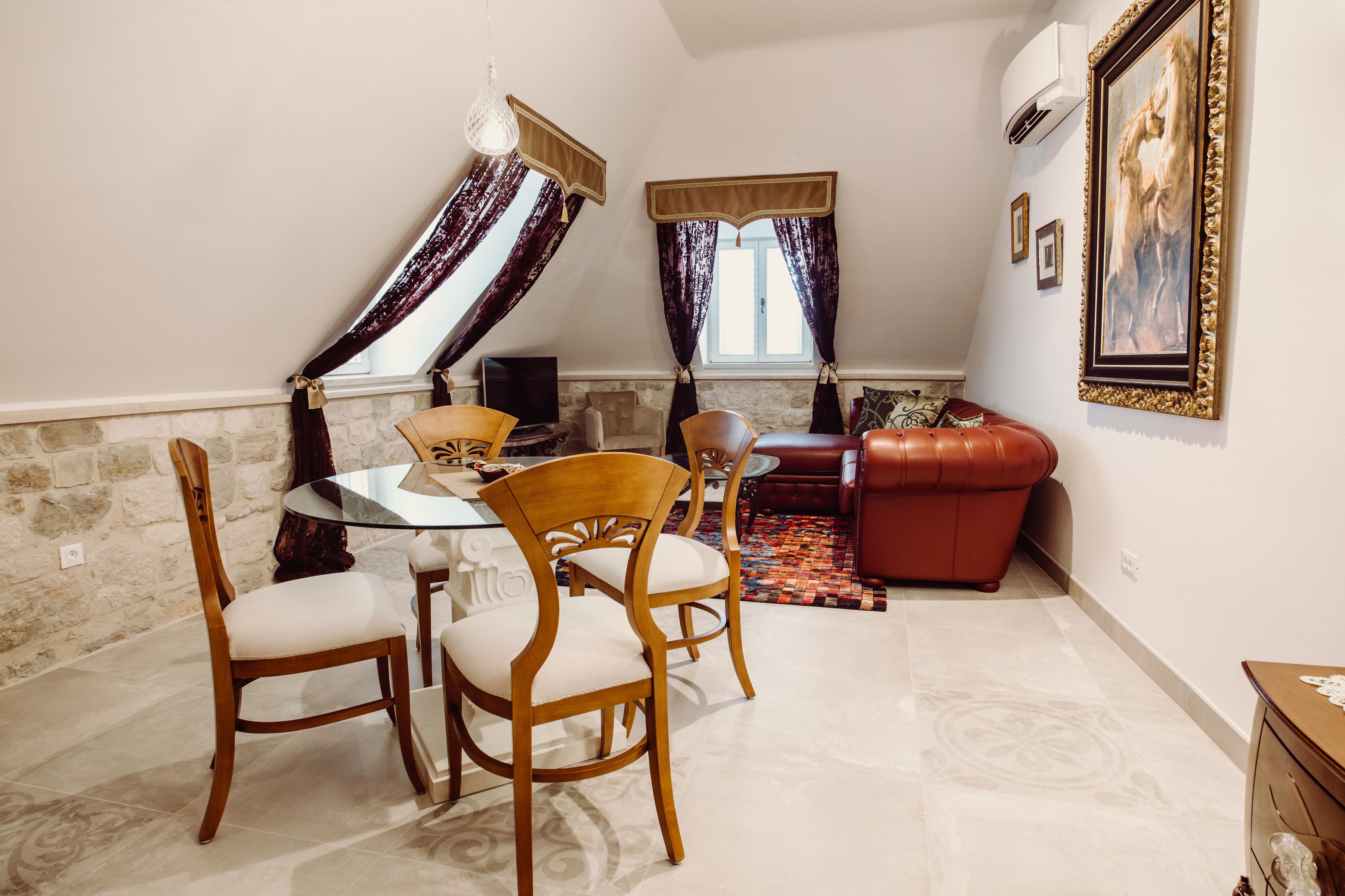 Un coin repas avec une table ronde et des chaises, un canapé rouge et un tapis à motifs.