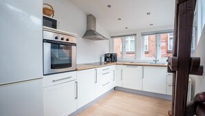 A modern kitchen with white cabinets, a stainless steel oven, and a built-in range hood. - Palads Hotel (Viborg)
