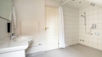 A bathroom with a white sink, a shower with a glass door, and a white radiator.