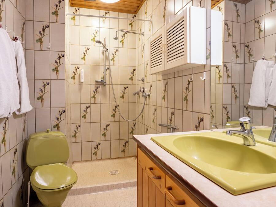 Casa de banho com lavatório amarelo, toalhas brancas e sanita.