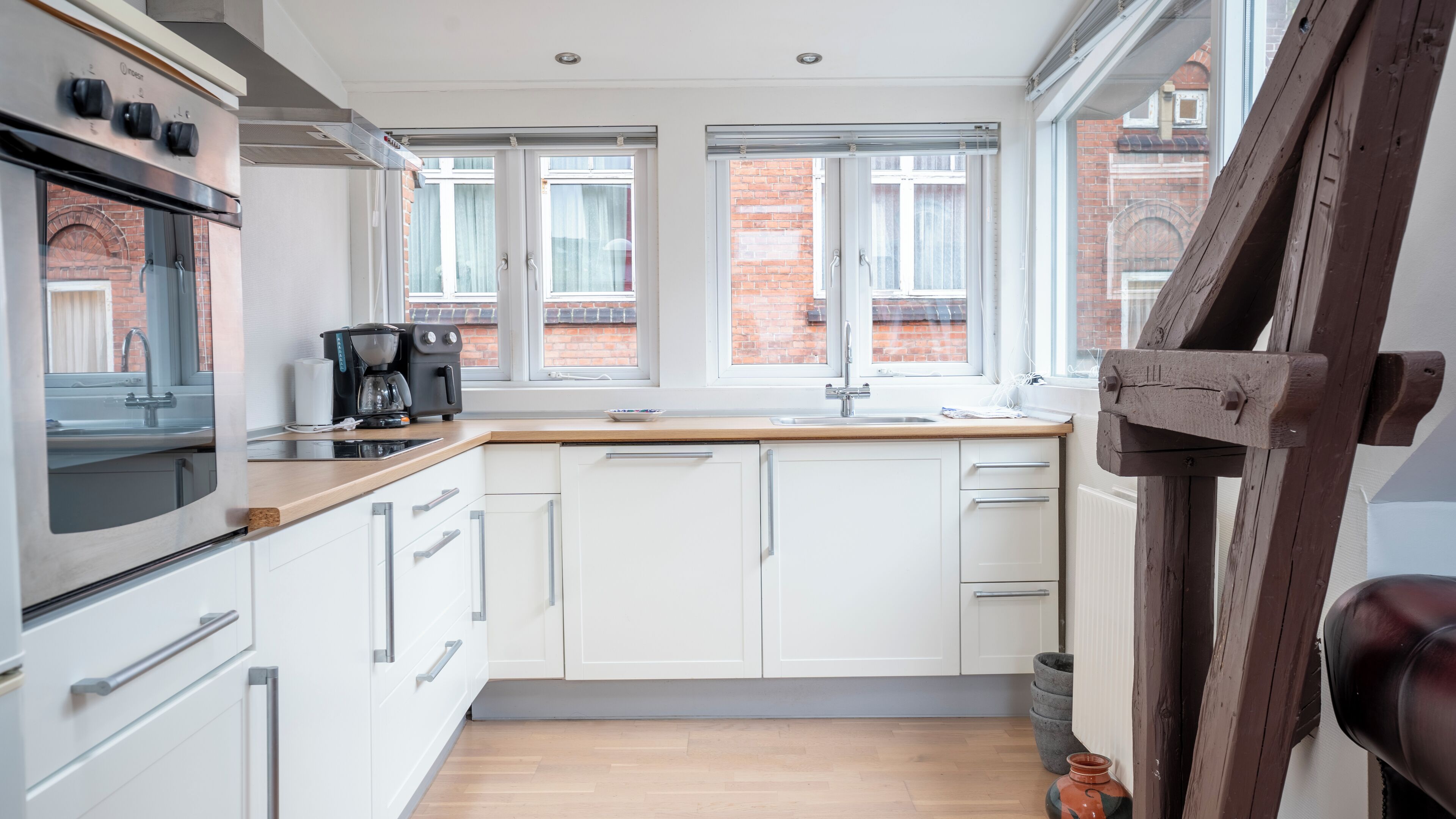 A modern kitchen with white cabinets, a wooden countertop, and a built-in oven.