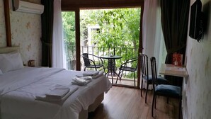 A hotel room with a bed, a small table, two chairs, and a balcony with a view of greenery. - Buyukada Cinar Hotel  (Adalar)