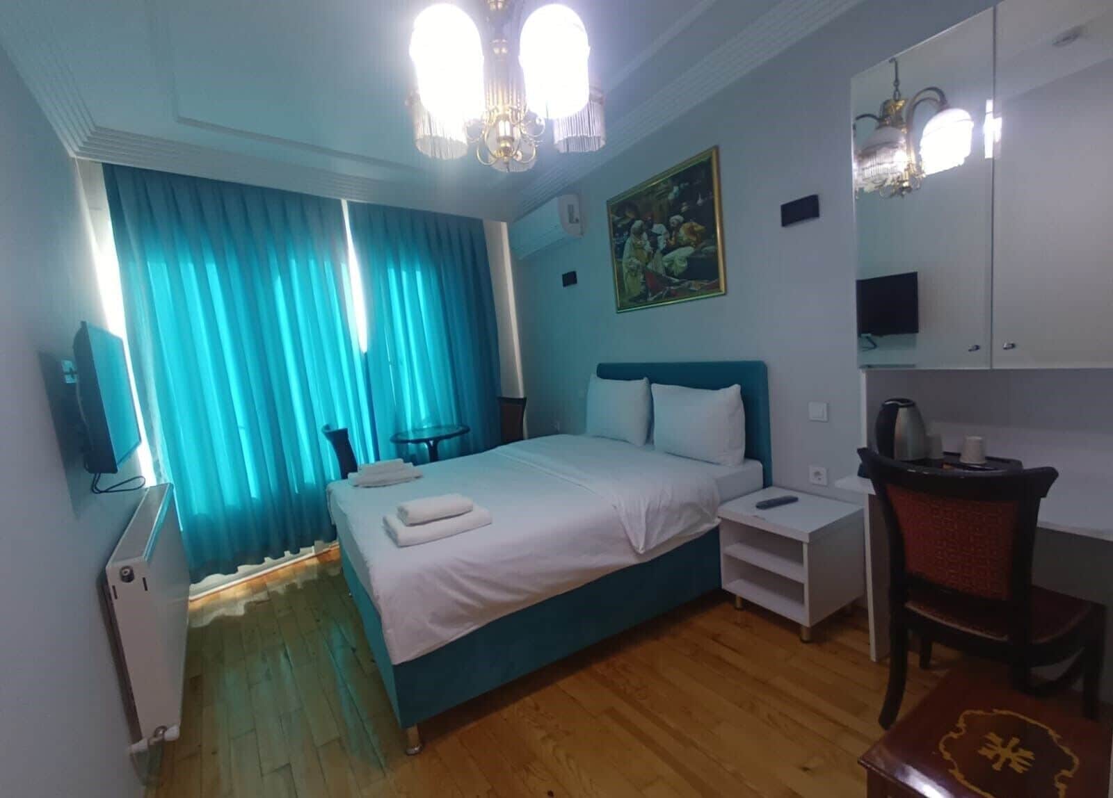 Ein Hotelzimmer mit Bett, Schreibtisch, Stuhl, Fernseher und einem Bild an der Wand.