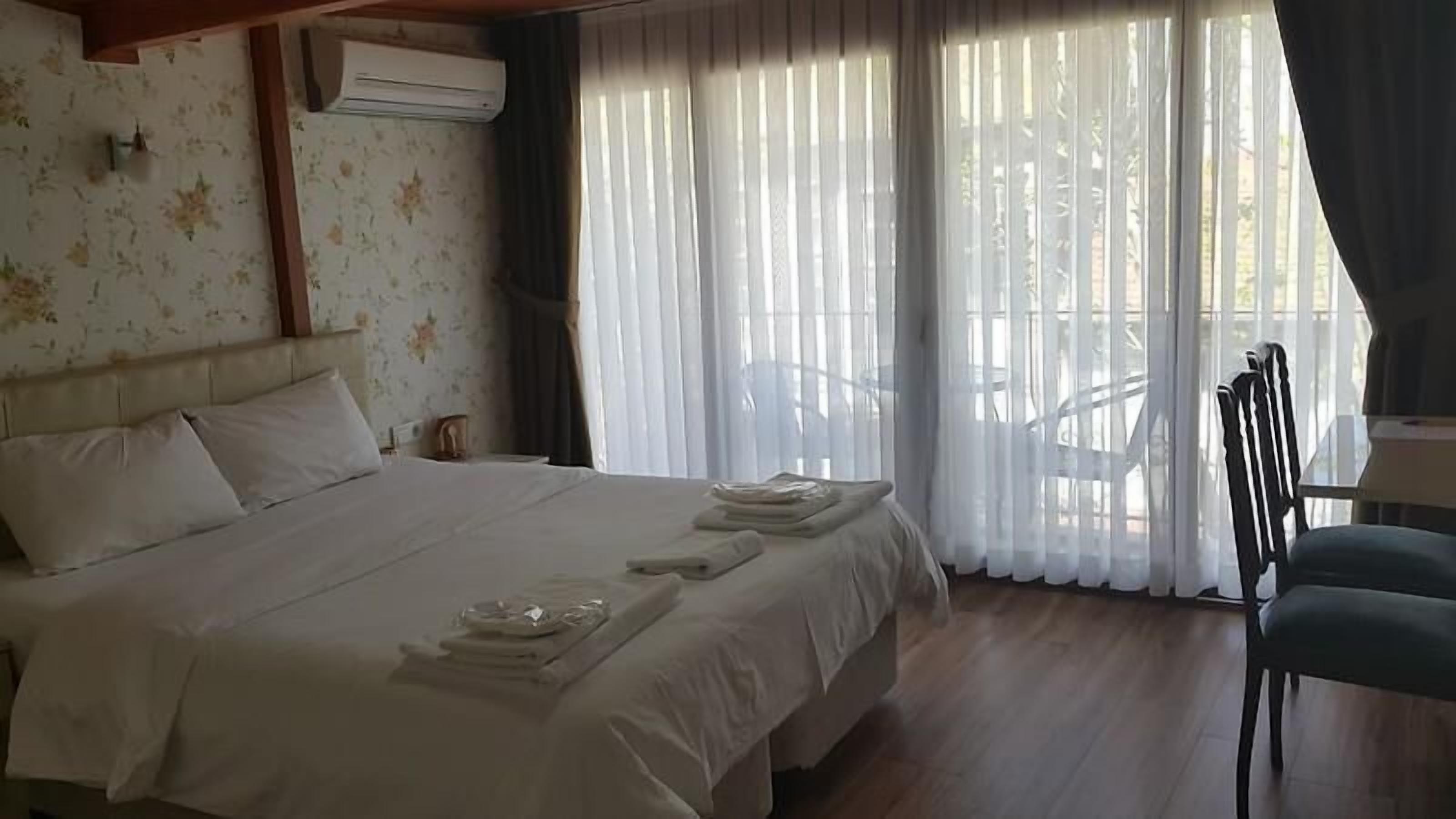 A hotel room with a bed, a chair, a table, and a balcony with a view.