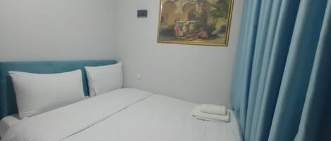 A hotel room with a bed, a painting on the wall, and a telephone.