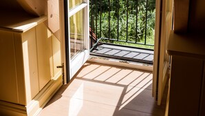 A wooden interior with a sliding glass door leading to a balcony with a metal railing, overlooking a forested area. - Romantisches Fachwerkhaus (Aumuehle)
