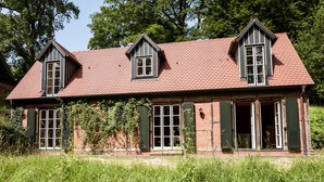 A two-story house with a red-tiled roof, green shutters, and a brick facade. - Romantisches Fachwerkhaus (Aumuehle)