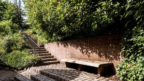A set of stone steps leading up to a brick wall with a metal railing and a bench. - Romantisches Fachwerkhaus (Aumuehle)