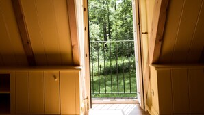 A bedroom with a wooden ceiling and a window leading to a balcony with a view of trees. - Romantisches Fachwerkhaus (Aumuehle)