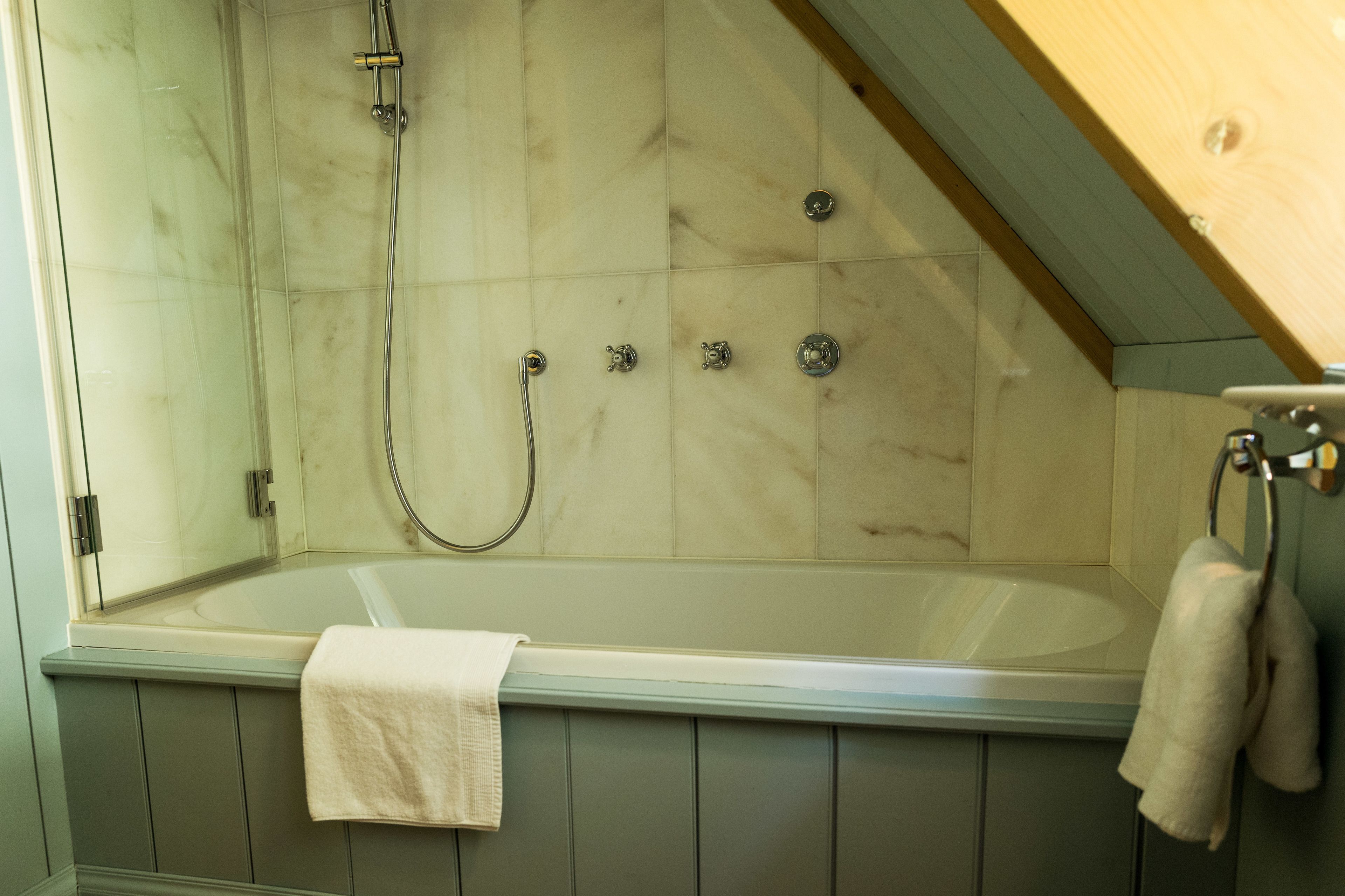 A bathroom with a bathtub, a shower, and a towel rack.