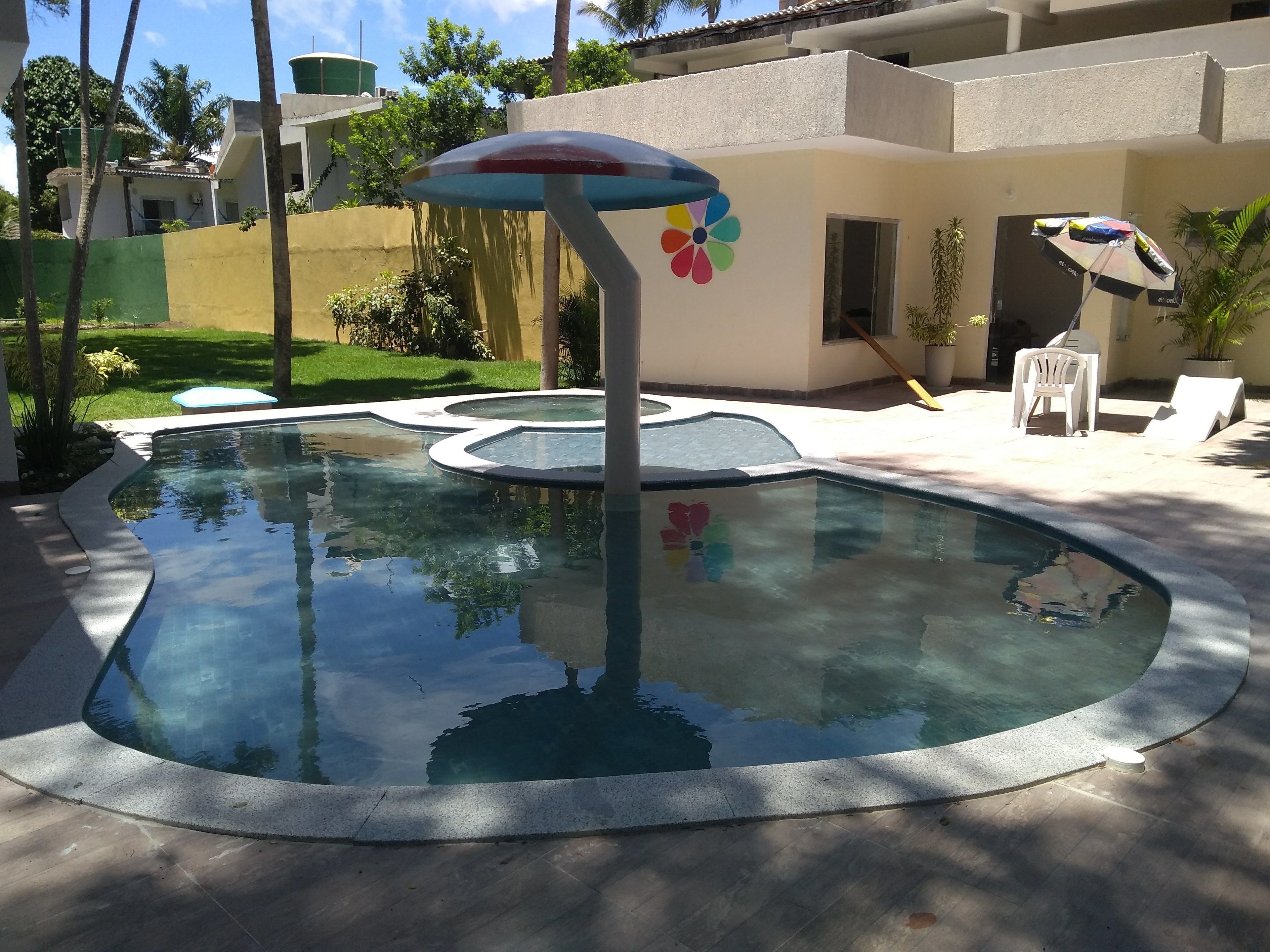 A swimming pool with a unique design, surrounded by a patio area with lounge chairs and umbrellas.
