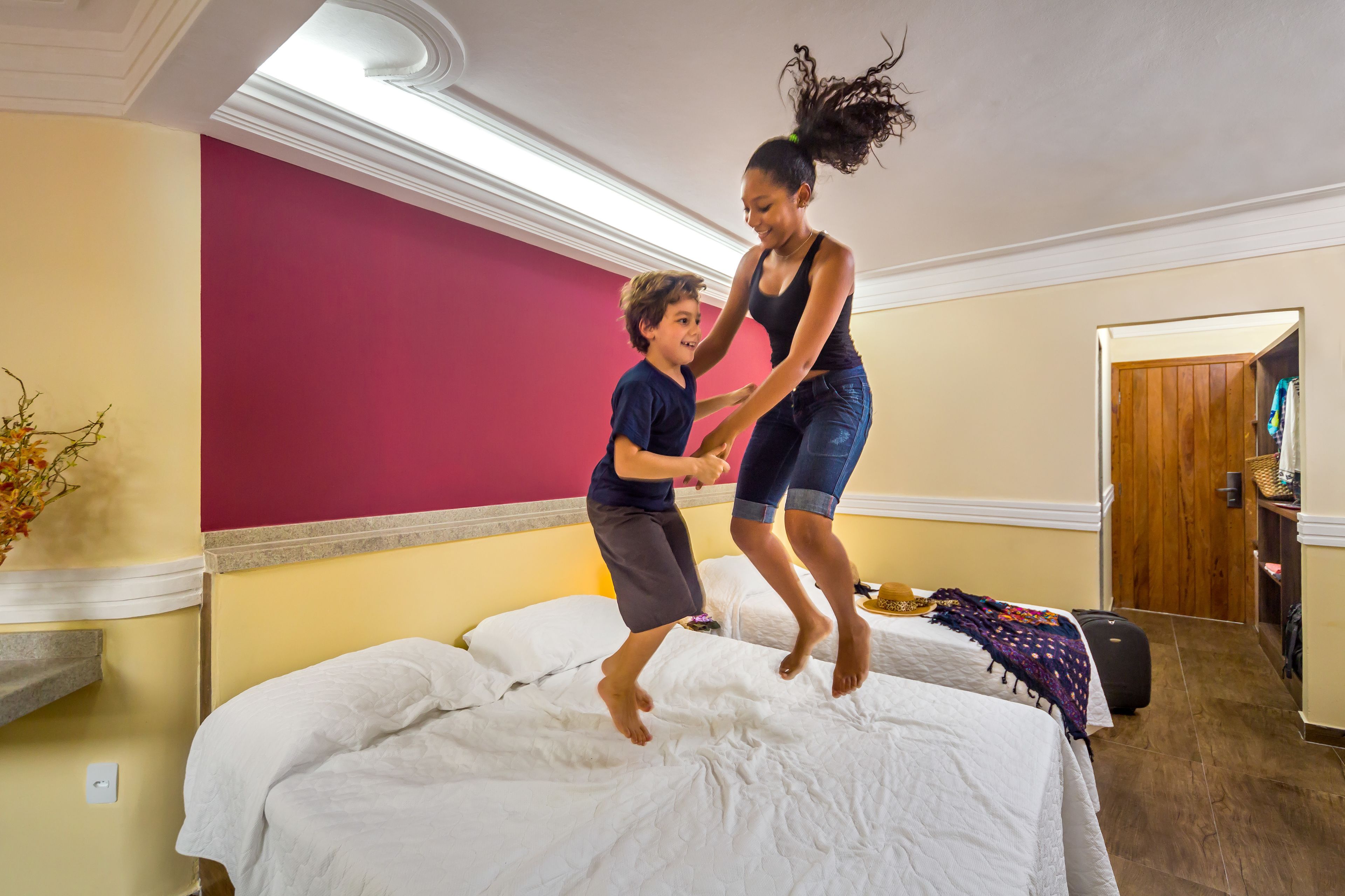 Una habitación con cama, una puerta de madera y una mesita con una cesta.