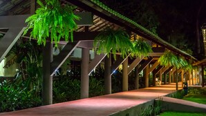 An outdoor pathway with hanging ferns, a covered walkway, and a well-maintained garden area. - Floral Inn Family Hotel (Porto Seguro)