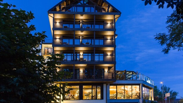 A multi-story hotel with balconies, large windows, and a dining area visible. - Alojamientos Ainsa Sanchez (Ainsa)