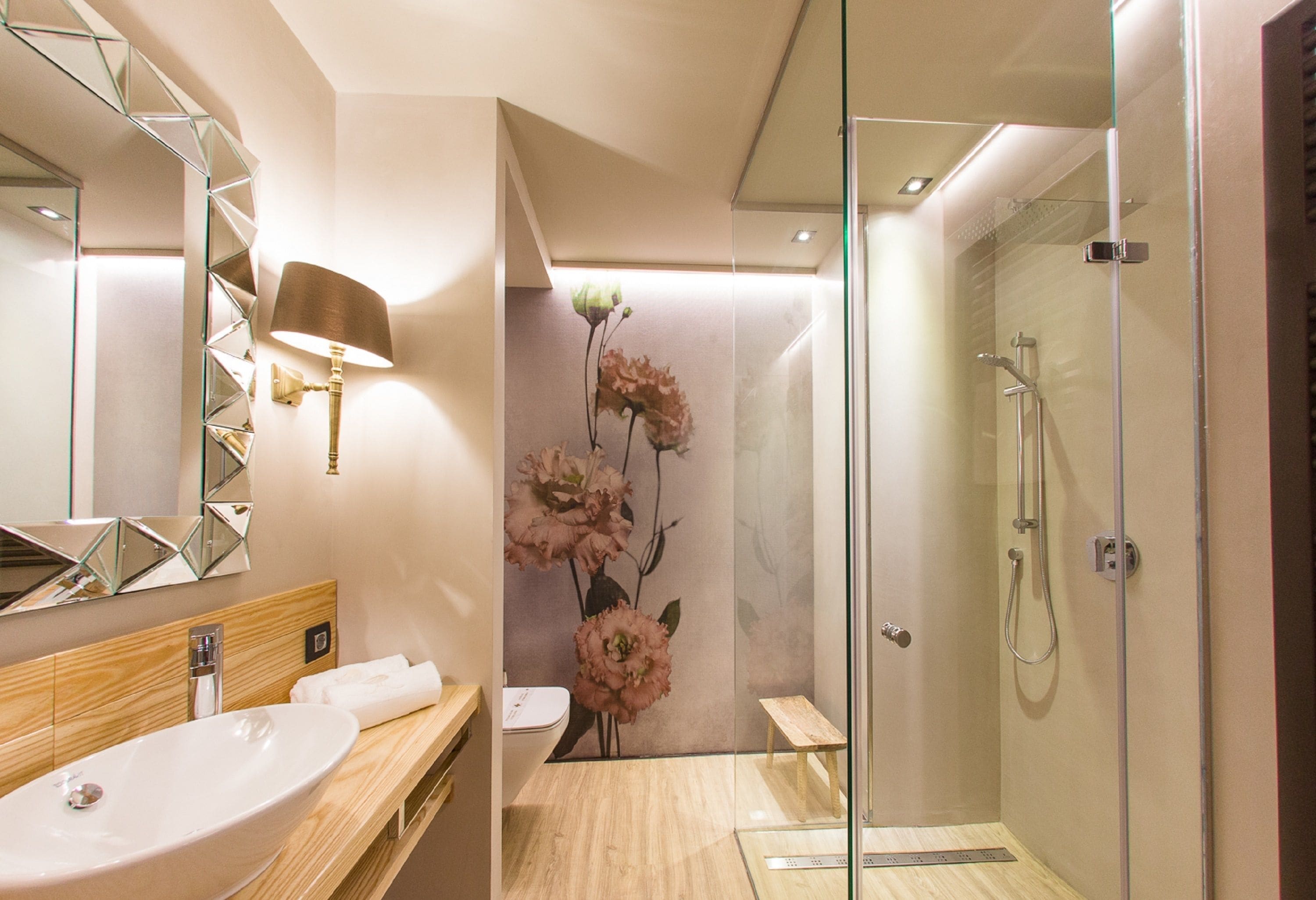 A modern bathroom with a large mirror, a sink, a shower, and a decorative wall with flowers.