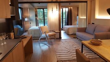 A modern hotel room with a wooden desk, a sofa, a dining table, and a bed.