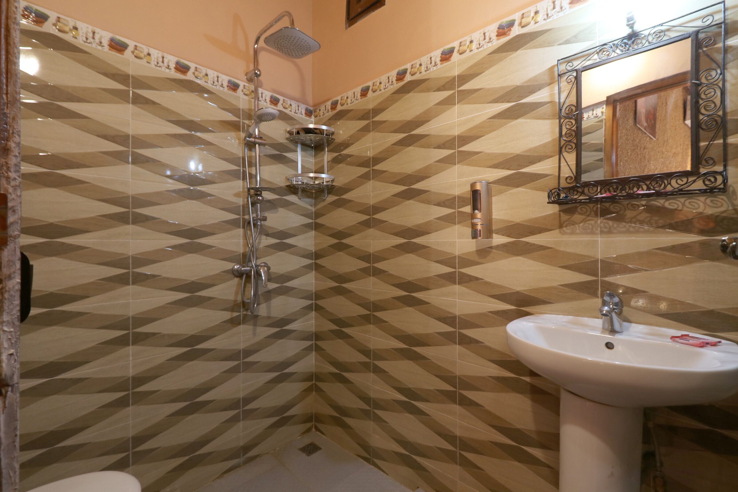 A bathroom with a shower, sink, and a decorative mirror.