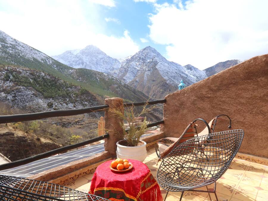 A balcony with a table, chairs, and a potted plant.